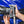 A close up of a person putting a nozzle into the holder on a TRC Ultra H2O Spray Gun with a blurry blue car in the background.