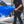 A person spraying water onto a blue car using a TRC Ultra H2O Spray Wand.