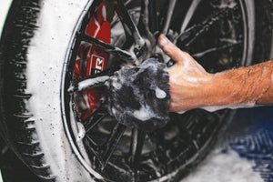 A person cleaning a tire rim with an Ultra Wool Wheel Mitt.