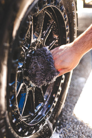 A person cleaning a tire rim with the Ultra Wool Wheel Mitt.