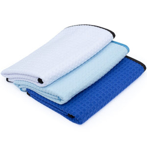 A picture of three Dry Me A River waffle weave microfiber towels from The Rag Company. THe colors are White, Light Blue, and Royal Blue with a black border