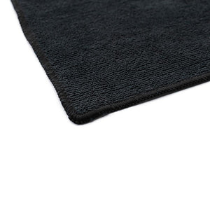 The corner of a black towel on a white background.