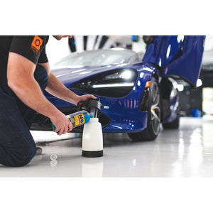 A person pouring Optimum No shine into an IK Sprayer with a blue sports car in the background.