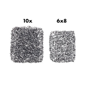 Two similar sized black and white microfiber wash pads on a white background