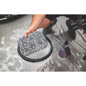 White and black wash pad held above a bucket after being used for a rinse less wash